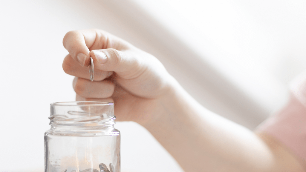 A person putting coins in a jar