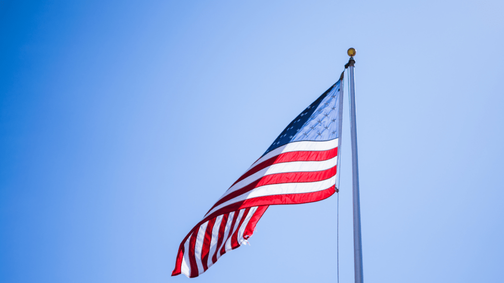 an american flag blowing in the wind against a blue sky