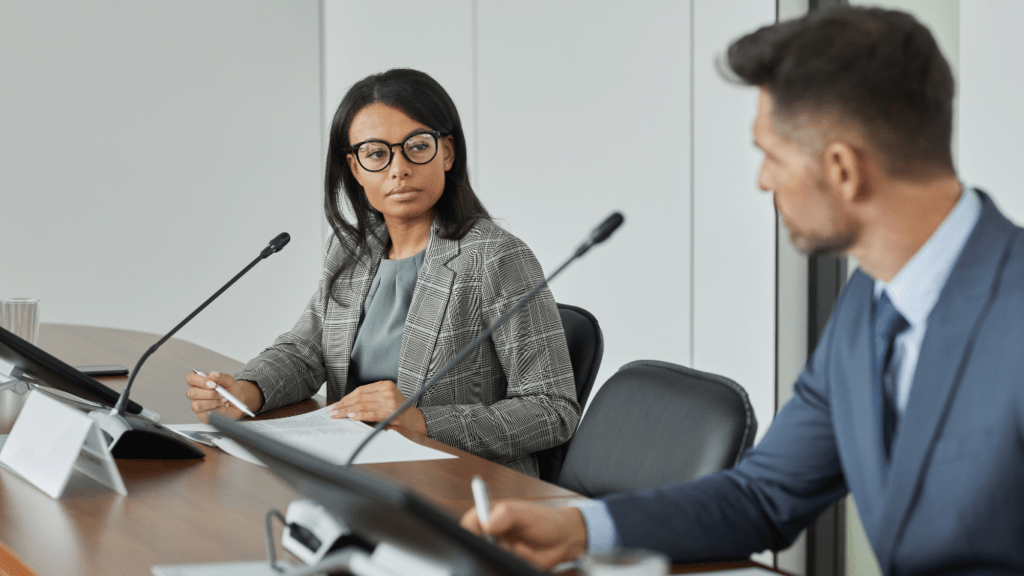 Two people sitting at a conference table in front of a microphone