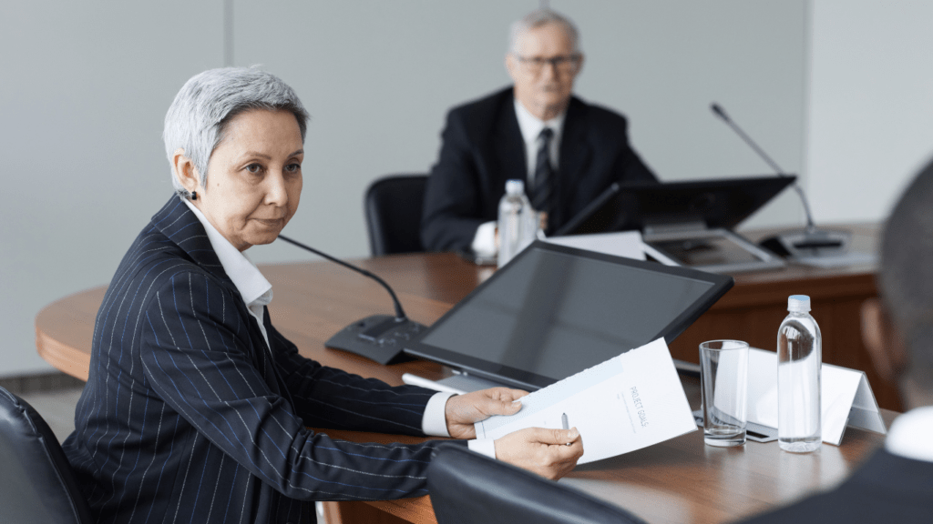 Two people sitting at a conference table in front of a microphone