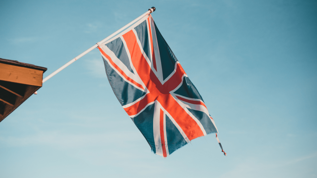 a british flag flying in the wind against a blue sky