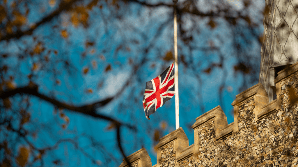 a british flag flying in the wind against a blue sky