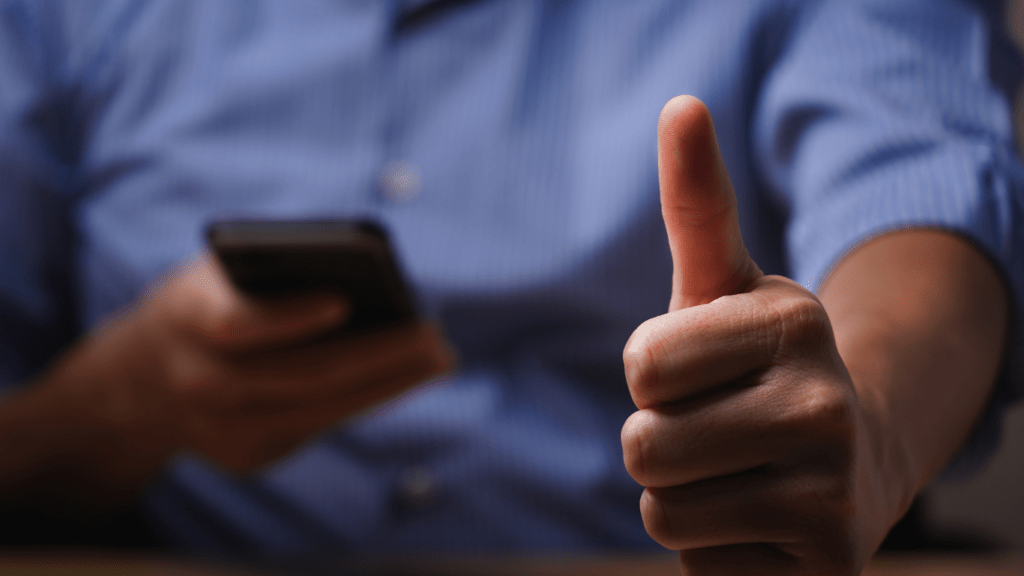 a person giving the thumbs up with a cell phone in front of them