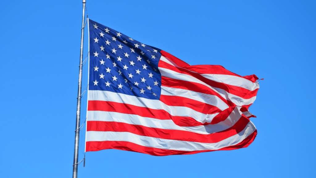 an american flag blowing in the wind against a blue sky