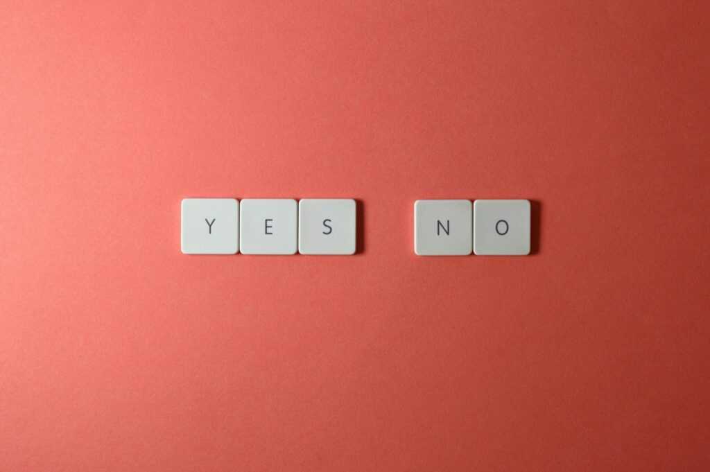 A conceptual image featuring 'yes' and 'no' text on white tiles against a red background, perfect for decision-making themes.